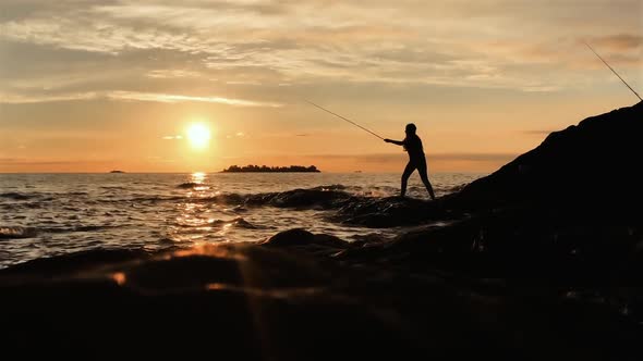 Silhouette of a Young Woman fishing at Sunset on the Beach. alt