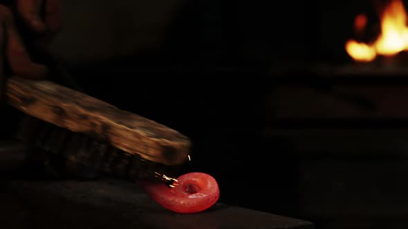 Hand of blacksmith using wire brush on hot iron alt