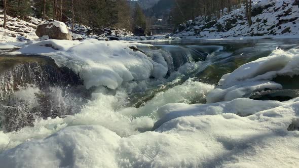Strong Flow of a Mountain River Covered with Snow in Winter