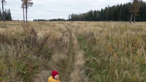Boy Child in a Yellow Vest and Red Hat Runs alt
