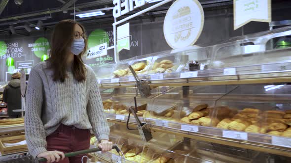 Closeup of a Young Woman's Hands Moving a Grocery Cart Through the Aisles of a Supermarket the alt