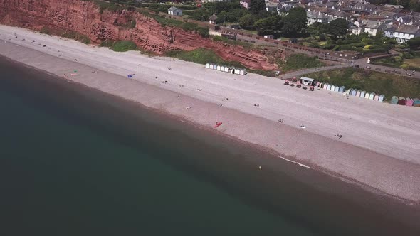 Aerial view of rusty red Triassic cliffs, pebble beach, sea and seafront of Budleigh Salterton. Jura alt