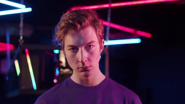 A Closeup Portrait of a Cute Teenager in a Blue Tshirt in a Computer Club in Neon Light alt