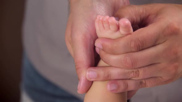 The Masseur Gives a Massage To the Baby. The Masseur's Hands Are Kneading the Baby's Feet. Massage