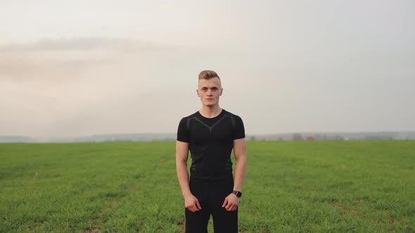 The Athlete is Standing on a Field with Green Grass alt