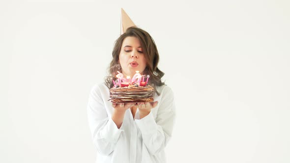 a Happy Lonely Woman with a Birthday Cake with Candles on a White Background alt