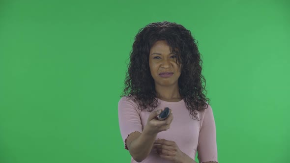 Portrait of Beautiful African American Young Woman with TV Remote in Her Hand, Switching on TV alt