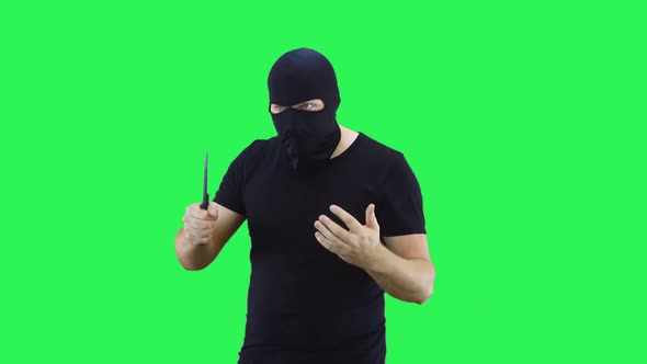 A man in a black mask holds a knife in his hand, showing his strength