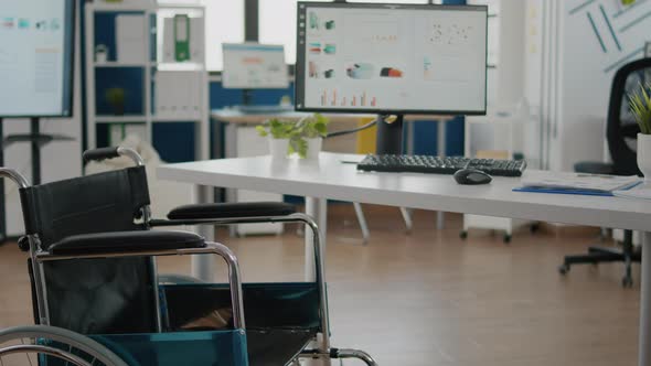 Wheelchair Parked in Empty Office Room Near Desk in Start Up Company alt