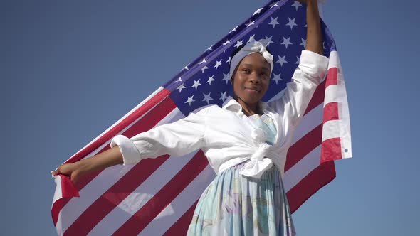 Confident African American Young Woman with USA Flag Posing at Background of Clear Blue Sky alt