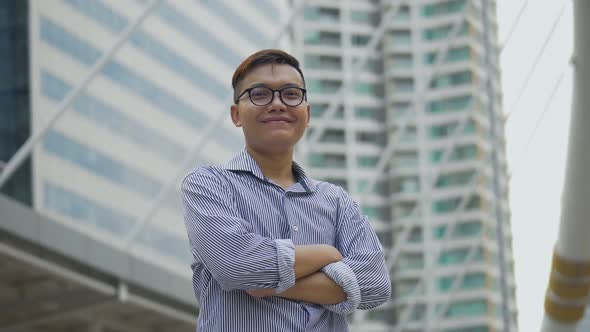 Portrait handsome Asian businessman smiling and looking at camera standing on the urban city.