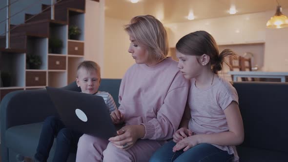 Mother Using Laptop at Home with Her Two Kids