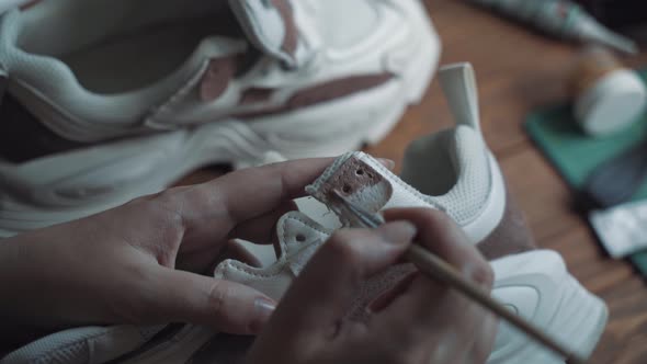 Person's Hand with Brush Paints White Sneaker