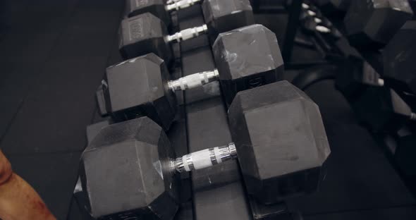 Male Hands Taking Bodybuilding Dumbbells In Gym Club. Closeup Man Hands Taking Weight alt