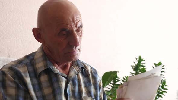 caucasian pensioner 70 years old at home looking at a stack of photos holding in his hands. elderly  alt