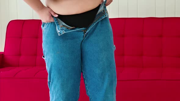 Overweight woman tries to wear pants that do not fit her size alt