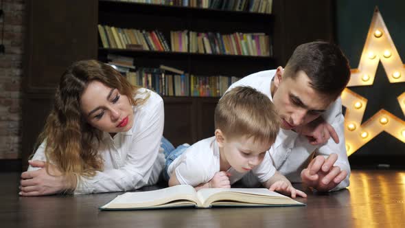 Portrait of Young Family Mom Son and Dad are Reading a Book Together alt