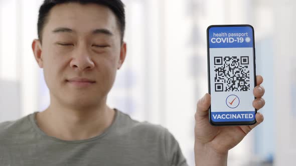 Portrait of Asian Male Person Showing Smartphone in His Hand with Mobile Application for Vaccination alt
