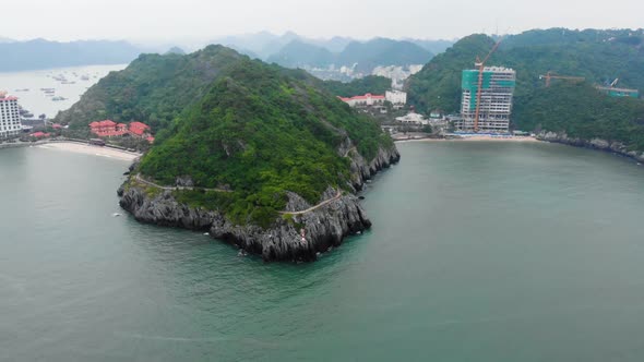 Aerial: flying over beautiful rocky coastline and promenade on the cliff at Cat Ba island, Vietnam alt
