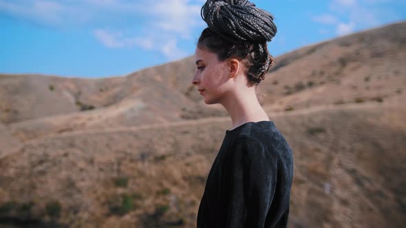 Adventure Trip  Young Woman Walks on the Top of a Mountain and Looking Around alt