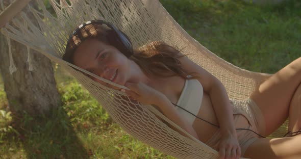 Girl Sleeps in Hammock Listening to Music Via Headphones