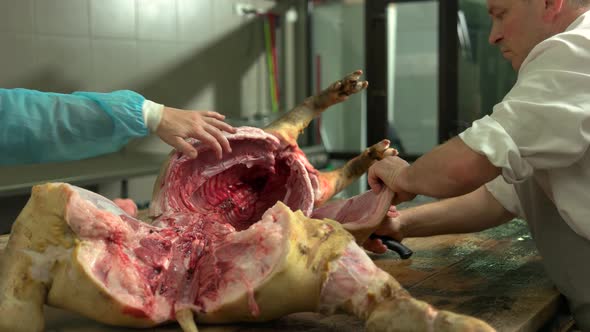 Butcher Cutting Pork Carcass at the Meat Manufacturing alt