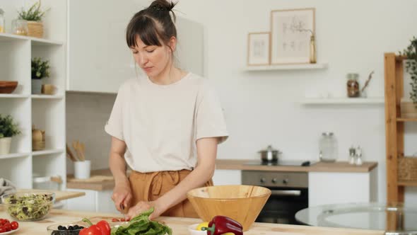 Young Woman Cooking Salad in Kitchen alt