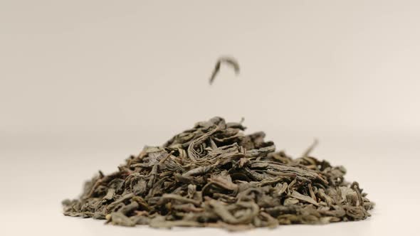 Tea leaves fall on a pile of a green tea