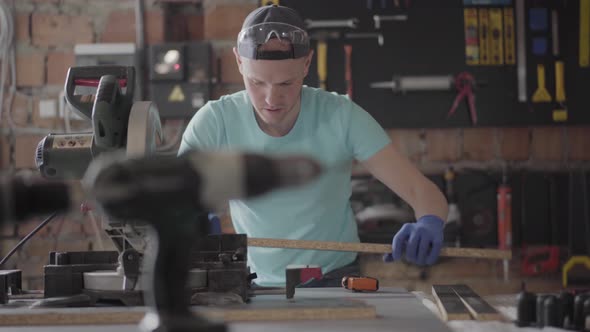 Skilled Carpenter Cutting a Piece of Chipboard Detail in His Woodwork Workshop, Using a Circular Saw alt