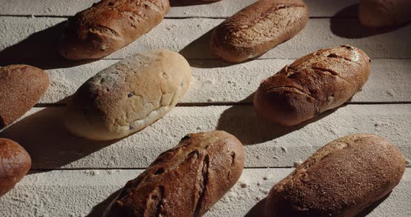A Variety Of Loaves Of Fresh Bread Are Laid Out On The Table And Sprinkled With Flour