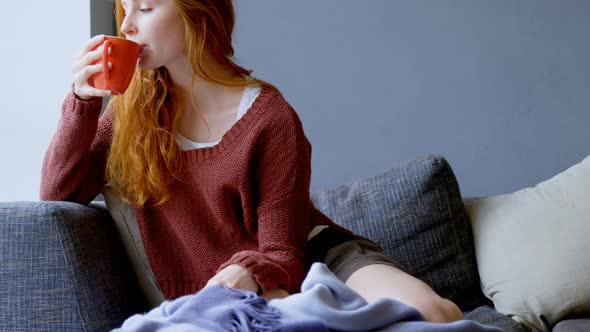 Woman having coffee in living room alt
