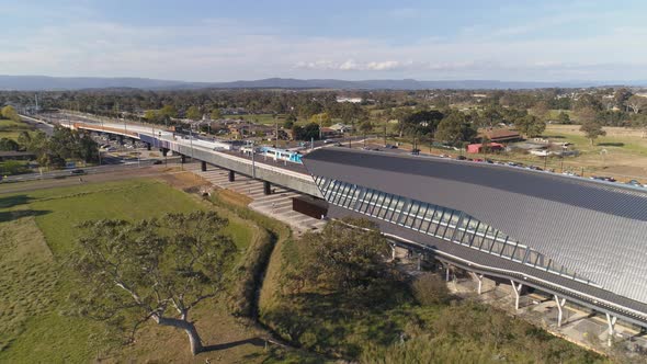 Aerial shot panning from Skatepark underneath train station to train line running overhead alt