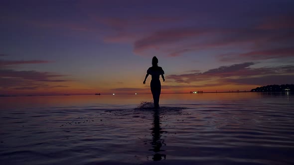 Young Woman Silhouette Walking in the Sea at Beautiful Sunset Thailand