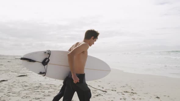 Young man on beach with surfboard alt