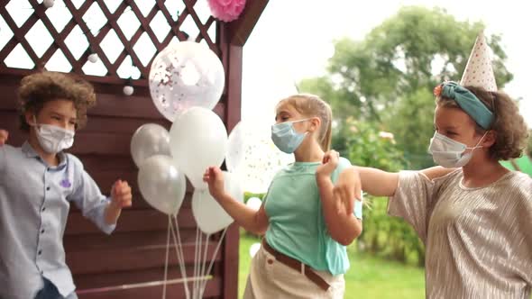 Teens in Protective Masks. Dancing at the Birthday Party in Masks. Happy Children During the Pandum alt