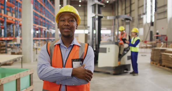 Portrait of african american male worker wearing safety suit and smiling in warehouse alt
