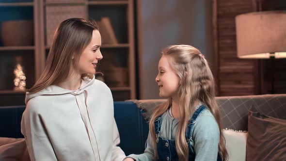 Happy Mother and Daughter Talking Spending Time Together at Home Evening with Floor Lamp Lighting