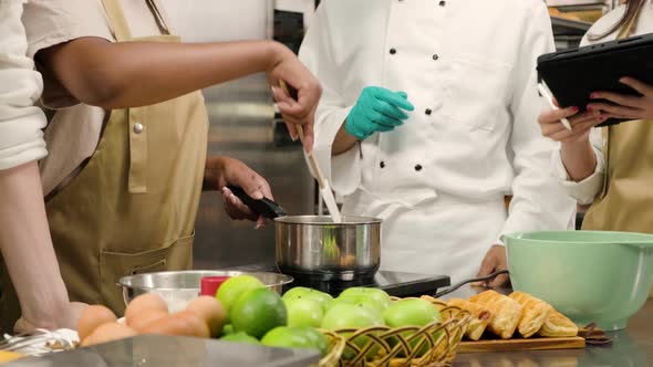 Senior male chef teaches cooking students to prepare ingredients for pastry. alt