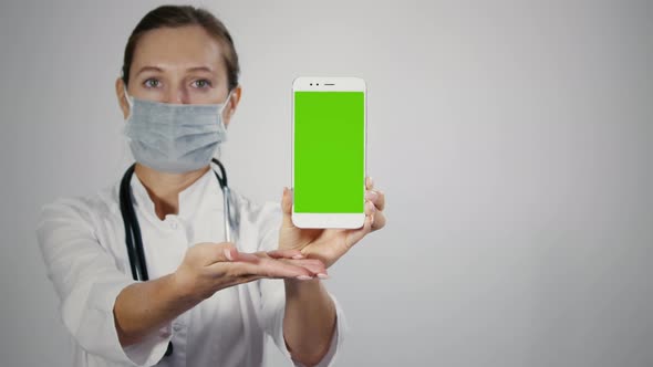 Female medical professional displaying mobile smartphone with greenscreen. alt