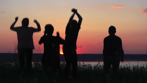 Silhouettes of Young People Have Fun at Sunset alt