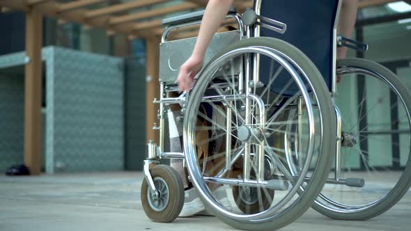 Young Woman in a Wheelchair. A Girl Rides in a Wheelchair Close-up Hand. Special Transport for the alt