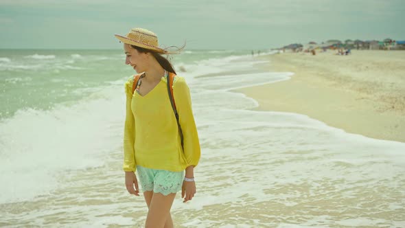 Happy Carefree Woman in Hat Walks Alons Sea Water at Sandy Beach Enjoying Find Sea Waves and Cloudy alt