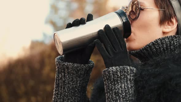 Stylish Young Woman Walking in Autumn City with Thermo Mug alt