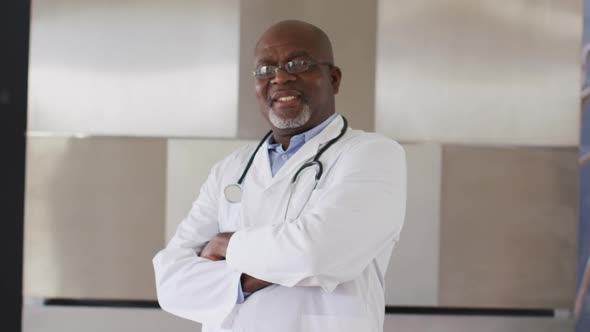 Smiling african american senior male doctor wearing white crossing his arms looking at the camera alt