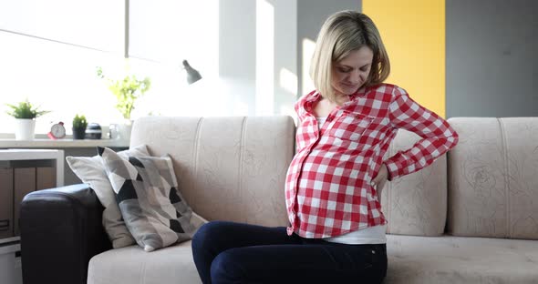 Pregnant Woman with Severe Back Pain on Couch Closeup alt