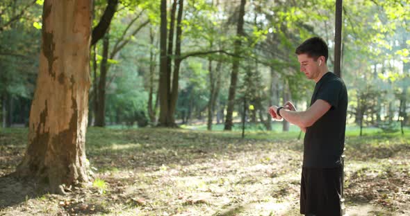 Adult Man Running Outdoor Using Wireless Bluetooth Earphones Listening to Music with Smartwatch alt