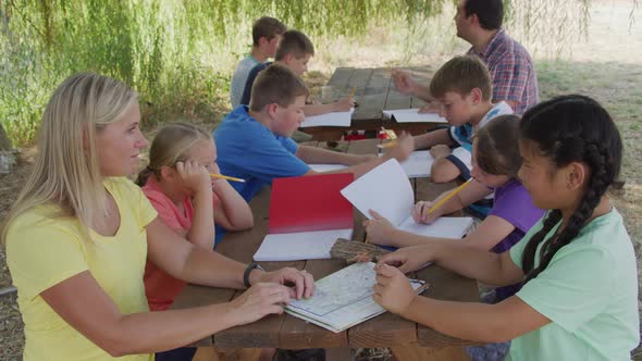 Kids at outdoor school writing in notebooks
