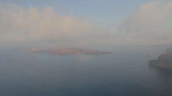 View of the majestic Santorini seascape including the volcano island of Nea Kameni. Foggy conditions alt