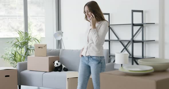 Woman moving in her new home and using her smartphone