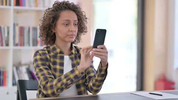 Unhappy Mixed Race Woman with Loss on Smartphone at Work alt